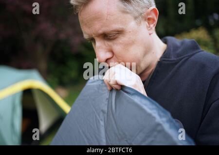 Nahaufnahme von Mann bläst ein selbst aufblasbare Schlafpolster für Camping Stockfoto