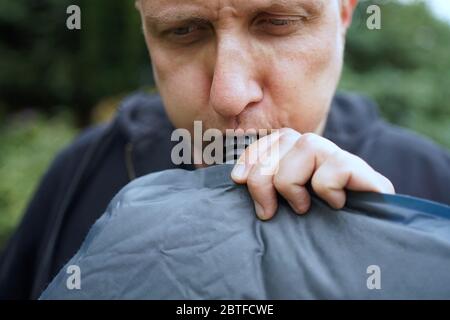 Nahaufnahme von Mann bläst ein selbst aufblasbare Schlafpolster für Camping Stockfoto