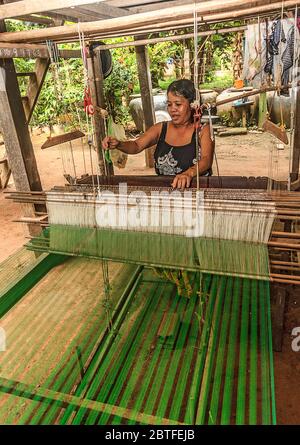 Seidenweberei auf Koh Dach Island, einer Insel vor dem Zentrum von Phnom Penh, Kambodscha. Hier webt eine Frau Seidenstoff von Hand auf einem Webstuhl unter ihrem Haus. Stockfoto