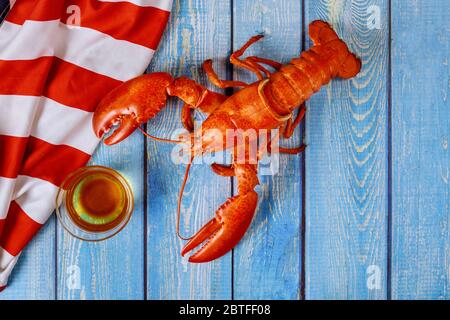 Amerikanische Ferienkost hausgemachte gekochte rote Hummer auf feine Auswahl an Krustentieren zum Abendessen auf einer zerzausten amerikanischen Flagge Stockfoto