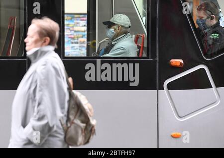 Eine Frau ohne Gesichtsmaske fährt in Prag am Montag, den 25. Mai 2020, an den Fahrgästen der Straßenbahn vorbei, die Gesichtsmasken tragen, wenn viele Maßnahmen gegen den Coronavirus aufgehoben werden, wie das obligatorische Tragen von Gesichtsmasken im Freien, heute in der Tschechischen Republik, wenn die Innenräume von Restaurants und Hotels, Camps und andere Unterkünfte werden nach mehr als zwei Monaten wieder eröffnet und Veranstaltungen für bis zu 300 Personen können durchgeführt werden. Ab heute müssen die Menschen keine Gesichtsmasken oder andere Nasen- und Mundschutz draußen tragen, sofern sie mindestens zwei Meter Abstand halten, außer für Mitglieder des gleichen Haushalts. Die Masken sind immer noch ma Stockfoto