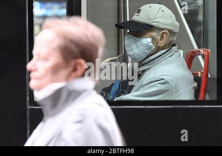 Eine Frau ohne Gesichtsmaske fährt in Prag am Montag, den 25. Mai 2020, an den Fahrgästen der Straßenbahn vorbei, die Gesichtsmasken tragen, wenn viele Maßnahmen gegen den Coronavirus aufgehoben werden, wie das obligatorische Tragen von Gesichtsmasken im Freien, heute in der Tschechischen Republik, wenn die Innenräume von Restaurants und Hotels, Camps und andere Unterkünfte werden nach mehr als zwei Monaten wieder eröffnet und Veranstaltungen für bis zu 300 Personen können durchgeführt werden. Ab heute müssen die Menschen keine Gesichtsmasken oder andere Nasen- und Mundschutz draußen tragen, sofern sie mindestens zwei Meter Abstand halten, außer für Mitglieder des gleichen Haushalts. Die Masken sind immer noch ma Stockfoto