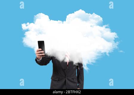 Geschäftsmann mit Kopf in den Wolken, der mit dem Handy die Wirtschaftskrise auf blauem Hintergrund berät. Surreales Konzept Stockfoto