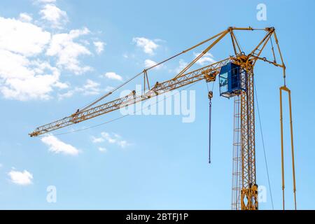 Industriebau Gebäudekran. Gelber mobiler Drehkran mit Kabine des Betreibers gegen blauen Himmel. Große hohe Maschine Stockfoto