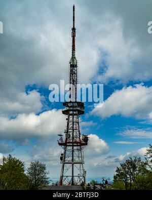Sendeturm auf der Spitze des Berges mit schönen Wolken und blauem Himmel im Hintergrund. Stockfoto