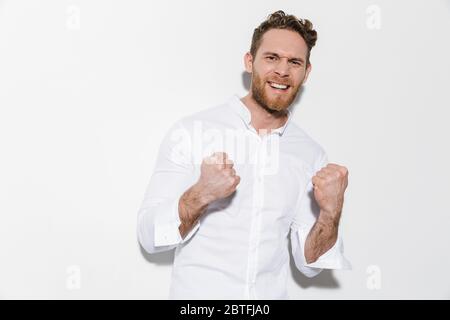 Bild von gutaussehend aufgeregt Mann im Hemd machen Gewinner Geste und lächeln isoliert auf weißem Hintergrund Stockfoto