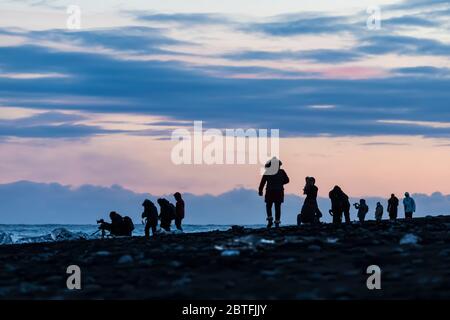 Fotografen mit schmelzenden Stücken aus klarem Gletschereis, die ursprünglich vom Breiðamerkurjökull-Gletscher in die Lagune von Jökulsárlón eingekalbt wurden, bei Diamond Beac Stockfoto