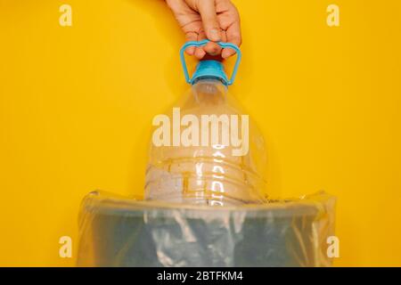 Ein Junge die Hand Einführung einer Plastikflasche für Recycling auf orangefarbenem Hintergrund, Recycling-Konzept Stockfoto