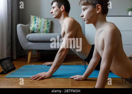 Junge mit seinem Vater, der Cobra Yoga Pose zu Hause auf Quarantäne. Stockfoto