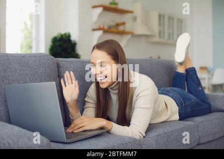 Mädchen blonde lächelt suchen nutzt Laptop Chat Anruf Anwendung in lässiger Kleidung liegen auf Sofa zu Hause. Stockfoto