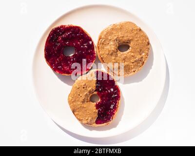 Ein Trio von Bagels, die in Erdnussbutter und Erdbeermarmelade erstickt wurden Stockfoto