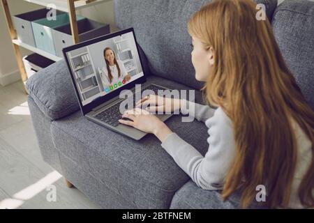 Arzt online. Mädchen Patient hört Video-Beratung Chat-Anruf mit weiblichen Arzt aus der Ferne sitzen auf dem Sofa zu Hause. Stockfoto