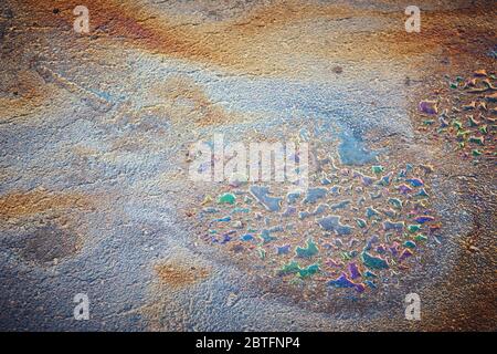 Ölfleck auf Asphalt nach Regen. Bunte giftige Flecken auf dem Parkplatz. Stockfoto