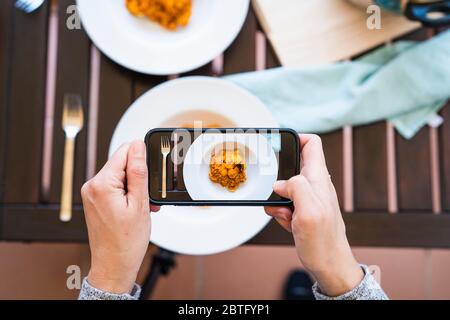 Frau, die mit ihrem Smartphone ein leckeres Gericht aus typischem Reis fotografiert. Stockfoto