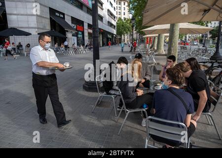 Ein Kellner, der eine Sanitärmaske trägt, wird gesehen, wie er seine Kunden an einem Terrassentisch bedient.Barcelona beginnt heute Phase 1, die die Installation von Barterrassen und Restaurants auf öffentlichen Straßen ermöglicht, wobei die Abstände zwischen den Tischen aufgrund der Covid-19-Infektion respektiert werden. Stockfoto