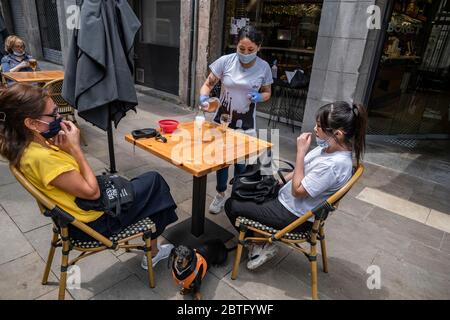 Ein Kellner, der eine Sanitärmaske trägt, wird gesehen, wie er seine Kunden an einem Terrassentisch bedient.Barcelona beginnt heute Phase 1, die die Installation von Barterrassen und Restaurants auf öffentlichen Straßen ermöglicht, wobei die Abstände zwischen den Tischen aufgrund der Covid-19-Infektion respektiert werden. Stockfoto