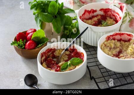 Hausgemachtes Sommerdessert. Erdbeeren bröckeln in einer Backform auf einer Tischplatte aus Stein oder Schiefer. Stockfoto