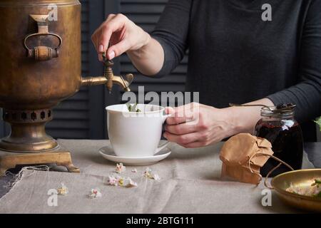 Seitenansicht der weiblichen Hände Gießen Tasse Tee aus Vintage Samowar und Glas hausgemachte Marmelade, Tee Party-Konzept Stockfoto