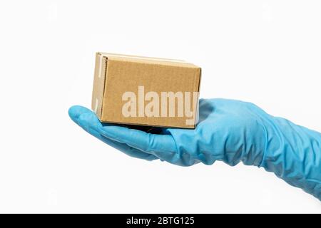 Lieferung Mann hält Karton in Gummihandschuhe. Online-Shopping und Paketzustellung während der Coronavirus COVID-19 Pandemie Stockfoto