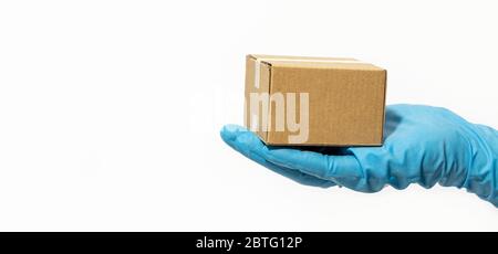 Lieferung Mann hält Karton in Gummihandschuhe. Online-Shopping und Paketzustellung während der Coronavirus COVID-19 Pandemie. Kopierbereich. Banner Stockfoto