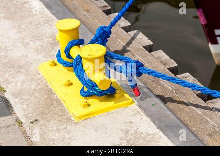 Liefer- objekte Konzept. Segeln Seile gebunden um Gelbe marina Pins. Außenaufnahme an einem sonnigen Tag. Stockfoto