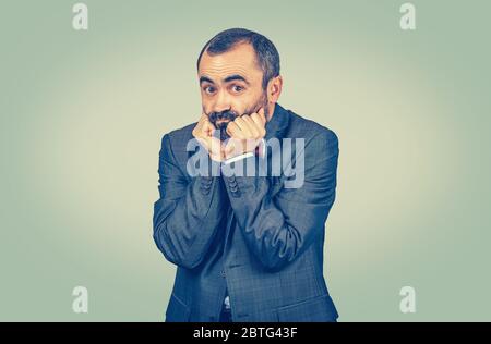 Portrait ängstlich mittleren Alters bärtigen Mann beißt seine Nägel Finger Ausflippen isoliert auf grün gelb einheitliche Verlauf Hintergrund. Stockfoto