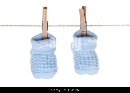 Blaue Babybooties hängen an der Wäscheleine mit Holzpflöcken Stockfoto