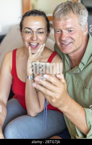 Glückliches Paar mittleren Alters, das ein Mobiltelefon sucht Stockfoto