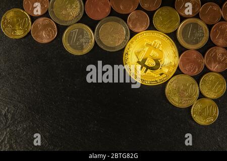 Goldene Bitcoin-Münzen und Euromünzen auf schwarzem Schiefergrund. Investitionen in virtuelle Währung. Europäische Finanzmittel. Stockfoto