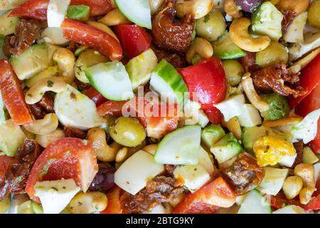 Ein gesunder, hausgemachter vegetarischer Salat nach mediterraner Art mit Gurke, roter Paprika, Mozzarella, Cashewnüssen, sonnengetrockneten Tomaten, Oliven & Ei Stockfoto