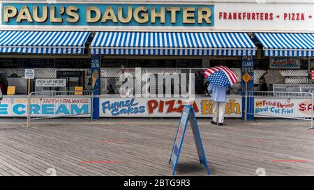 New York, New York, USA. Mai 2020. New York, New York, USA: Ein Mann trägt einen amerikanischen Flagge Regenschirm, während er Essen bei Pauls Tochter in Coney Island am Memorial Day inmitten des Coronavirus Outbrak bestellt. Kredit: Corine Sciboz/ZUMA Wire/Alamy Live News Stockfoto