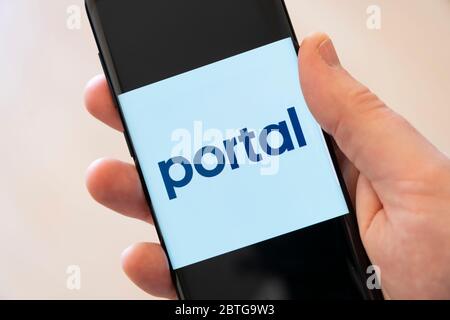 Eine Hand eines Mannes, der ein Handy hält und ein großes Logo für die Portal App von Facebook anzeigt, mit der du Portal-Geräte mit deinem Smartphone steuern kannst Stockfoto