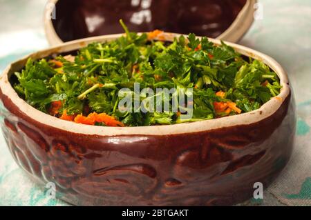 Kartoffeln in Töpfen zum Backen vorbereiten. Kartoffeln, Fleisch, Zwiebeln, Karotten, Petersilie in Keramiktopf. Ländliche Küche Stockfoto