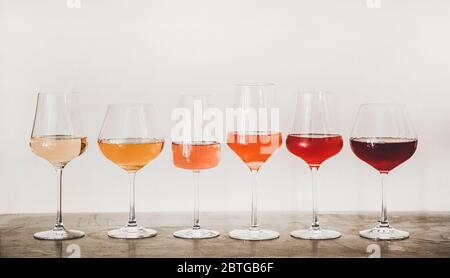 Nuancen von Roséwein in Gläsern auf Betontisch Stockfoto