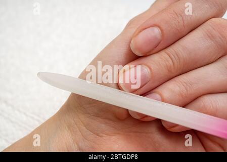 Frau feilend ihren Finger zu Hause. Weiblich poliert ihre Nägel zu sich selbst. Maniküre Verfahren Sie sich zu Hause. Stockfoto