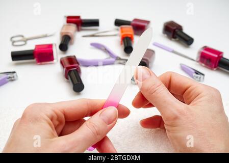 Frau feilend ihren Finger zu Hause. Weiblich poliert ihre Nägel zu sich selbst. Maniküre Verfahren Sie sich zu Hause. Stockfoto