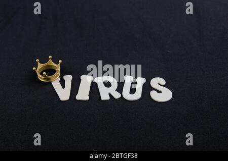 Eine kleine Krone und einige Holzbuchstaben bilden das Wort Coronavirus auf schwarzem Hintergrund. Stockfoto