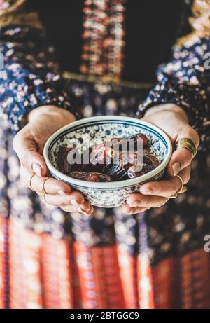 Frau in orientalischem Kleid hält Schüssel mit Datteln für Ramazan Stockfoto