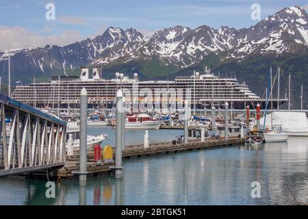 Kreuzfahrtschiff dockte im Seward Harbour in Seward, Alaska mit Kreuzfahrtschiff-Ladedock und Mount Alice und Bergkette im Hintergrund Stockfoto