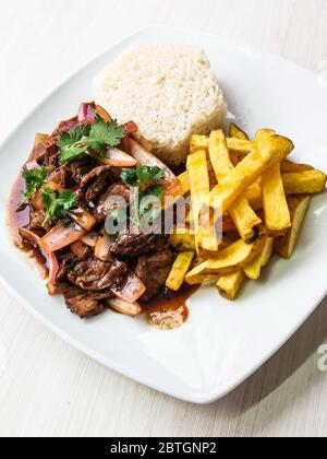 Traditionelles peruanisches Gericht Lomo Saltado (Beef Saltado). Lomo Saltado ist ein Rührbraten, der in der Regel marinierte Streifen von Sirloin mit Zwiebeln, Tomaten, pommes Frites kombiniert und in der Regel mit Reis serviert Stockfoto