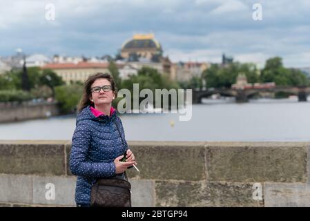 Eine Frau wird gesehen, wie sie auf der Karlsbrücke nach dem Aufheben der obligatorischen Regel, Gesichtsmasken zu tragen, eine Zigarette raucht.Pflichttragen von Schutzfacemasken aufgrund der Coronavirus-Pandemie, die am 19. März von der tschechischen Regierung eingeführt wurde, Wurde am 25. Mai zum Stillstand gebracht, aber Facemasken sind immer noch obligatorisch für öffentliche Verkehrsmittel und in Innenräumen, wo die Menschen nicht garantieren können, dass sie mindestens 2 Meter voneinander entfernt stehen. Stockfoto