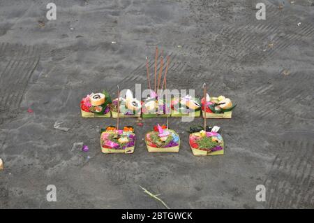 Opfergaben Set balinesischer und indonesischer Ritus Angebot an Gottheitsengel gott des Wassers im Meer auf Bodensand am Kuta Beach in Bali, Indonesien Stockfoto