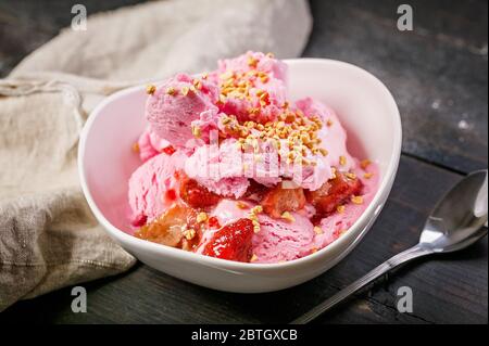 Erdbeersorbet mit Marmelade, Beeren und Puffreis in einer weißen Schüssel. Hausgemachte Köstliche Nachspeisen Stockfoto