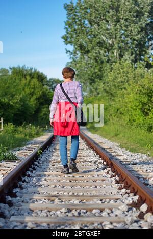 Rückansicht der älteren Frau, die auf den Spuren der Reilroad läuft Stockfoto