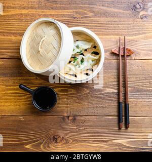 Japanische Gyoza oder Knödel Snack mit Sojasauce in Holzdampfer auf Holz japan Tabelle Draufsicht Stockfoto