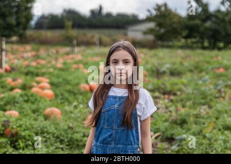 Nettes kleines Mädchen Porträt in einem Kürbis Patch mit verschwommenem Hintergrund. Stockfoto