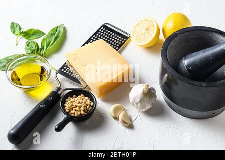 Italienische Küche Zutaten auf weißem Stein Hintergrund mit Parmesan-Käse, Basilikumblättern, Pinienkernen, Olivenöl, Zitrone, Knoblauch, Salz und Pfeffer legen Stockfoto
