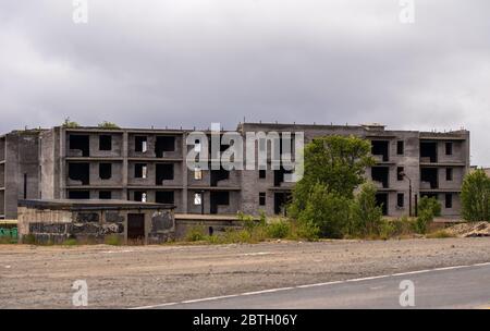 Fassade eines verlassenen grauen mehrstöckigen sowjetischen Plattengebäudes. Russische alte städtische Wohnhäuser ohne Fenster. Typische russische Nachbarschaft. Stockfoto