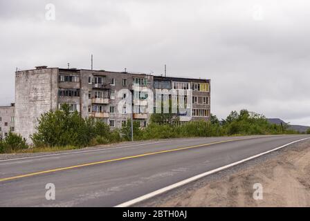 Fassade eines alten Ziegelgrauen mehrstöckigen sowjetischen Paneelgebäudes. Russische alte städtische Wohnhäuser mit Fenstern. Typische russische Nachbarschaft. Stockfoto