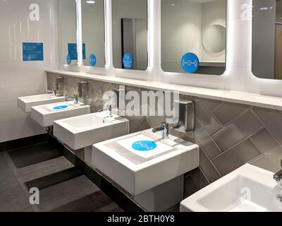 Distanzaufkleber und Schilder über den Waschbecken, Spiegel in einer öffentlichen Toilette für die Menschen, um soziale Distanzierung zu folgen, um eine Infektion der Coronavirus-Krankheit zu vermeiden. Stockfoto